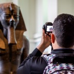 A person taking a photo of a Pharaoh's bust at the British Museum