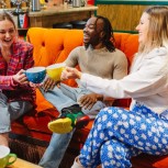 Three friends raising mugs on the couch at Central Perk