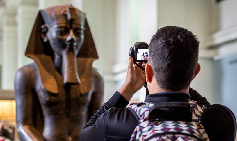 A person taking a photo of a Pharaoh's bust at the British Museum