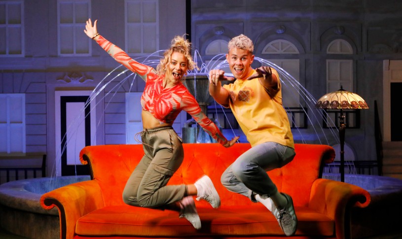 Two friends jumping in front of the couch and fountain