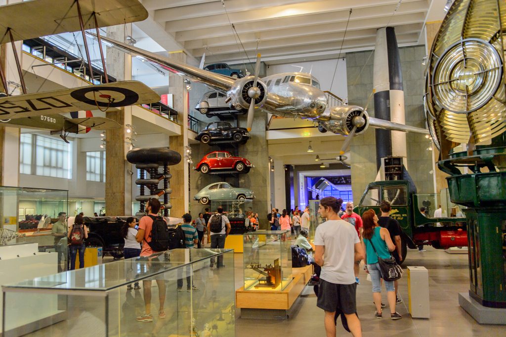 A photo of the Science Museum in London - cars are stacked against the wall with a plane suspended from the ceiling.